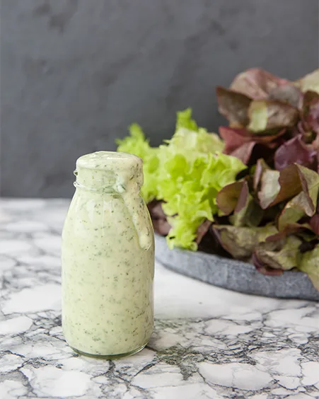 bottle of homemade yogurt dressing with fresh herbs