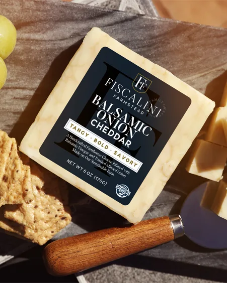 a block of fiscalini balsamic onion cheddar cheese is surrounded by sliced cubes