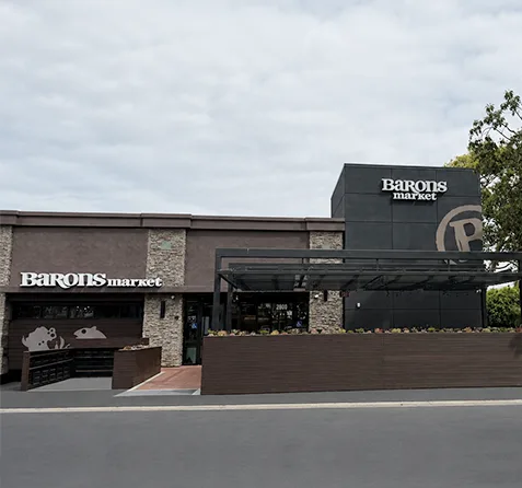 A modern storefront of Barons Market under a cloudy sky